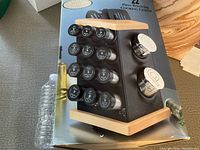 Photo of unopened boxed 22 piece revolving cooking center showing black body with wooden top and bottom and labeled spice jar lids on sides.