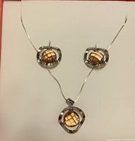 Front view of the pendant necklace and matching earrings on a white display background, showing the faceted stones and silver settings clearly.