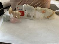 Photo of five small stone animal figurines displayed on a white surface including elephants, fish, and hippopotamus.
