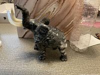 Side view of black and white stone elephant figure with trunk raised and white curved tusks, showing polished texture.