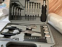Open carrying case showing the tool set inside including Allen wrenches, screwdriver bits and handle, pliers, adjustable wrench, and sockets