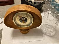 Side view of the barometer showing wooden frame shape and depth next to a water bottle for scale