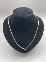 Full view of the gold herringbone necklace displayed on a black bust, showing its length and chain pattern.