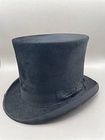Front three-quarter view of black top hat showing ribbon and brim