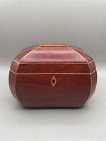 Front view of walnut wood jewelry casket with light wood inlaid border and keyhole.