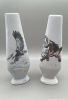 Pair of Chinese ceramic vases. One vase decorated with galloping horses and white splotches. The other vase decorated with an eagle in flight and pale blue splotches. Both vases white ceramic and approximately 9 inches tall.