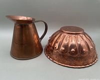 Photo of small handmade copper jug next to antique copper mold showing overall condition and details.