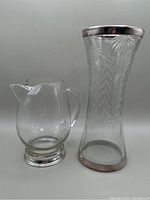 Photo of both glass items: an etched glass vase with sterling silver rim and base, and a clear glass pitcher with sterling silver base.