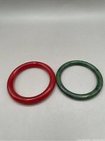Both bracelets shown side by side on a white surface: one red, one green.