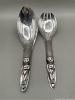 Front view of hammered silverplate salad spoon and fork with Kwakiutl figure handles
