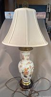 Full view of table lamp showing fabric lampshade and vase base with floral design