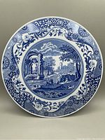 Front view of round Spode Italian blue and white ceramic trivet or cake stand showing detailed classical Italian landscape pattern with floral and scroll borders.