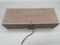 Closed brown suede Pandora jewelry box with wrap tie closure.