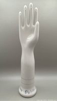 Front view of the white porcelain glove mold shaped as a hand, showing smooth glossy surface and size markings at base.