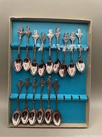 Full set of 15 silver plated souvenir tea spoons displayed in a blue lined case showing the busts of Canadian Prime Ministers on the handles.