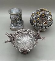 Overview of the three items showing two sterling silver Jerusalem-themed candle holders with gold accents and one bird-shaped decorative dish with textured interior and bird handles.