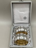 Two sterling silver napkin rings with gold wash inside displayed in their white lined box showing an interior fabric lining with a small logo or stamp.