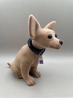 Side view of the tan felt-covered Chihuahua bobble head with black collar and Taco Bell logo tag