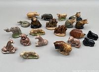 Overview of 21 assorted Wade ceramic figurines of zoo and farm animals arranged on a white background. Animals include giraffes, leopards, hippos, raccoons, dogs or wolves, fox, beaver, blackbird, turtle, and several small animals.
