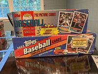 Two unopened boxes of Topps baseball cards from 1994 and 1993, stacked side by side showing packaging and branding details.