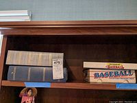 Two large albums and a Baseball Collector's Treasure Chest box on a wooden shelf