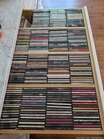 Drawer filled with CDs organized in rows, showing a dense collection of jewel cases with various music artists and genres.