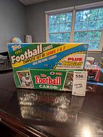 Two sealed boxes of 1992 Topps Football Cards including complete sets of Series 1 and 2 placed on a reflective table surface near a window.