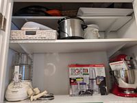 Shelf with Cuisinart food processor, Magic Bullet boxed blender, Crock-Pot, and party platters