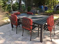 Front view of metal table with six lattice-back chairs and red cushions
