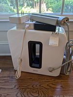 White Sonos Sub wireless subwoofer with cutout handle and attached cables, labeled lot sticker