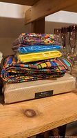 Stack of folded Fiesta pattern napkins and placemats stacked on top of a box.