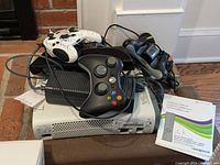 The Xbox 360 console on a surface with two controllers, Kinect sensor and two wired microphones.