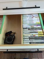 Xbox 360 games collection arranged in a drawer with visible titles and Atari joystick controller alongside