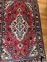 Close up of one smaller area rug with medallion and floral pattern in red tones