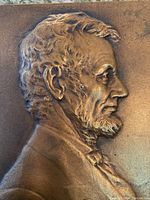 Close-up side profile of bronze relief showing Lincoln’s bust and textured details.