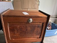 Closed view of antique wooden desk showing rotatable metal lock knob on front panel and wood grain finish.