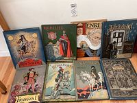 Seven hardcover albums upright against wall showing spines and covers