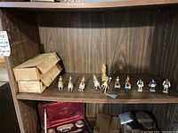 Full view of the lot on a wooden shelf, showing multiple knight figurines mounted on horses and two original packaging boxes.