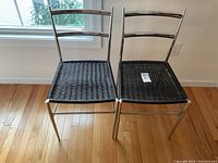 Front view of two small stainless steel desk chairs with black woven seats, showing their size and design.