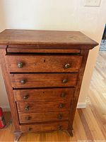 Front view of small wooden six drawer dresser with metal knobs, showing condition and design.