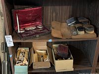 Overall display of top and bottom shelves showing leather case, suede roll case and three boxes of combs and accessories