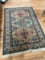 Full view of the rectangular Persian rug on a wooden floor, showing the multicolor geometric medallions and motifs with cream fringe ends.