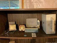 Wide view of wooden shelf displaying all items including a vintage clock, molecular models, blue Stillwell box, and Beam Converger casing.