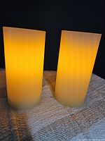 Pair of two flameless flickering candles illuminated, showing warm yellow light and smooth wax exterior.