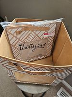 Photo showing two Thirty-One brand storage cubes with beige and light brown geometric design, fabric texture, and clear plastic window on front side of one cube.