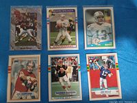 Seven football quarterback trading cards arranged in a grid visible on a blue background, showing Brett Favre, Dan Marino, Joe Montana, Jim Kelly, and Boomer Esiason cards.