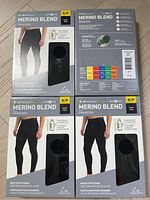 Four black men's small Paradox Merino Blend performance baselayers in original boxes with clear window showing fabric.