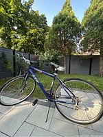 Full side view of CCM Speed 21 blue bicycle outdoors on paved patio, showing frame, wheels, seat, handlebars, and kickstand.