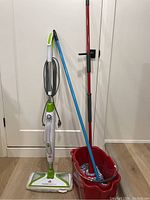 Full view of Bissell PowerFresh steam mop alongside red spin mop and blue traditional mop with red bucket.