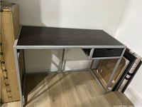 Front and side angle of the desk showing the dark wood top, metal frame, drawer on right